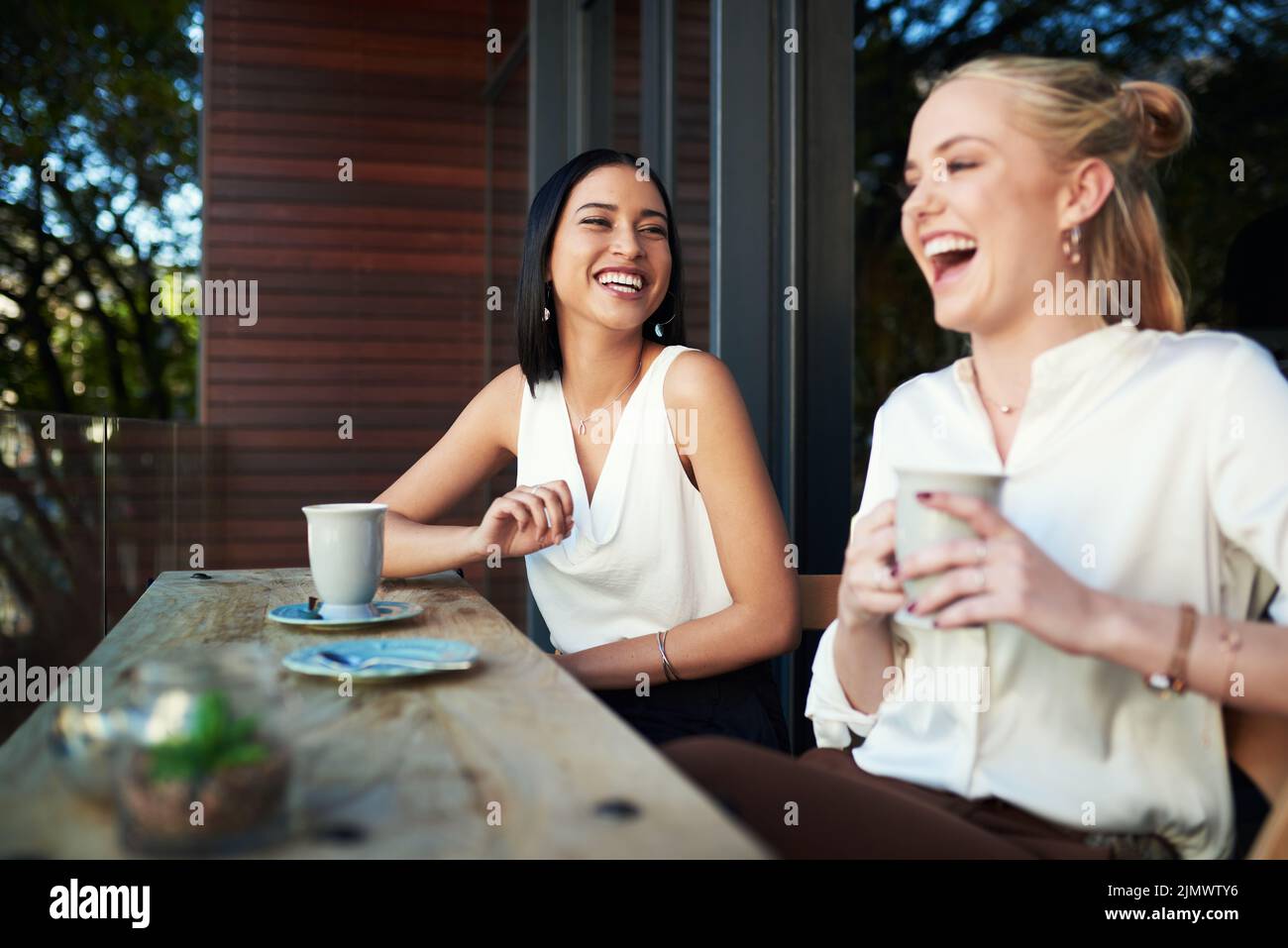 Avevamo bisogno di questa data del caffè: Due giovani donne che si divertano a vicenda mentre si gustavano un caffè in un bar. Foto Stock