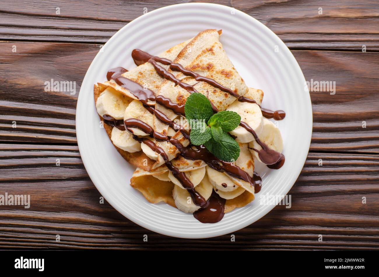 Piatto francese laici crepes con salsa di cioccolato e banana nel piatto di ceramica su legno tavolo da cucina Foto Stock