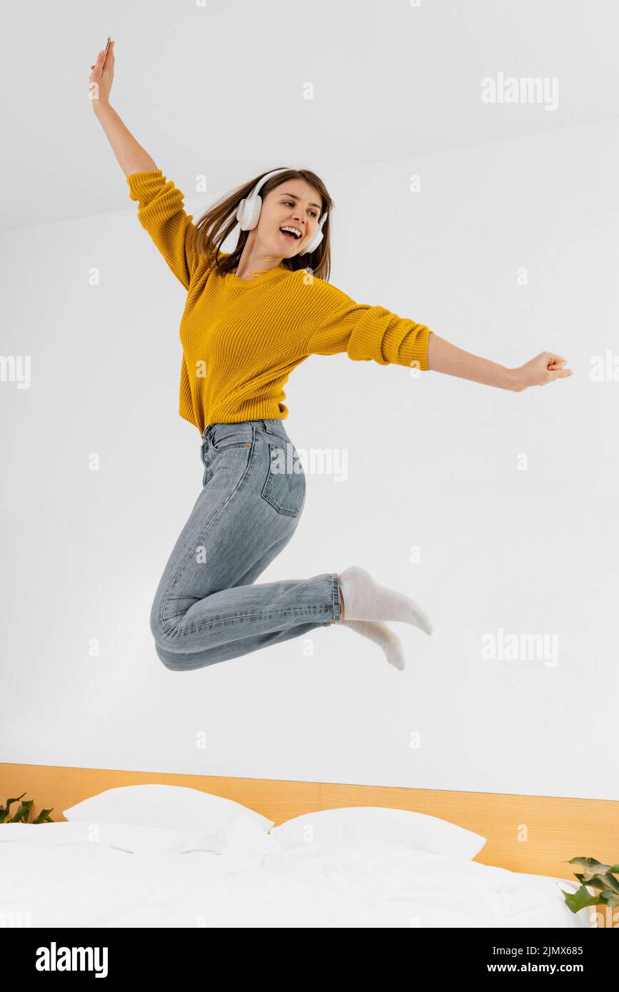 Donna che salta con le cuffie Foto Stock
