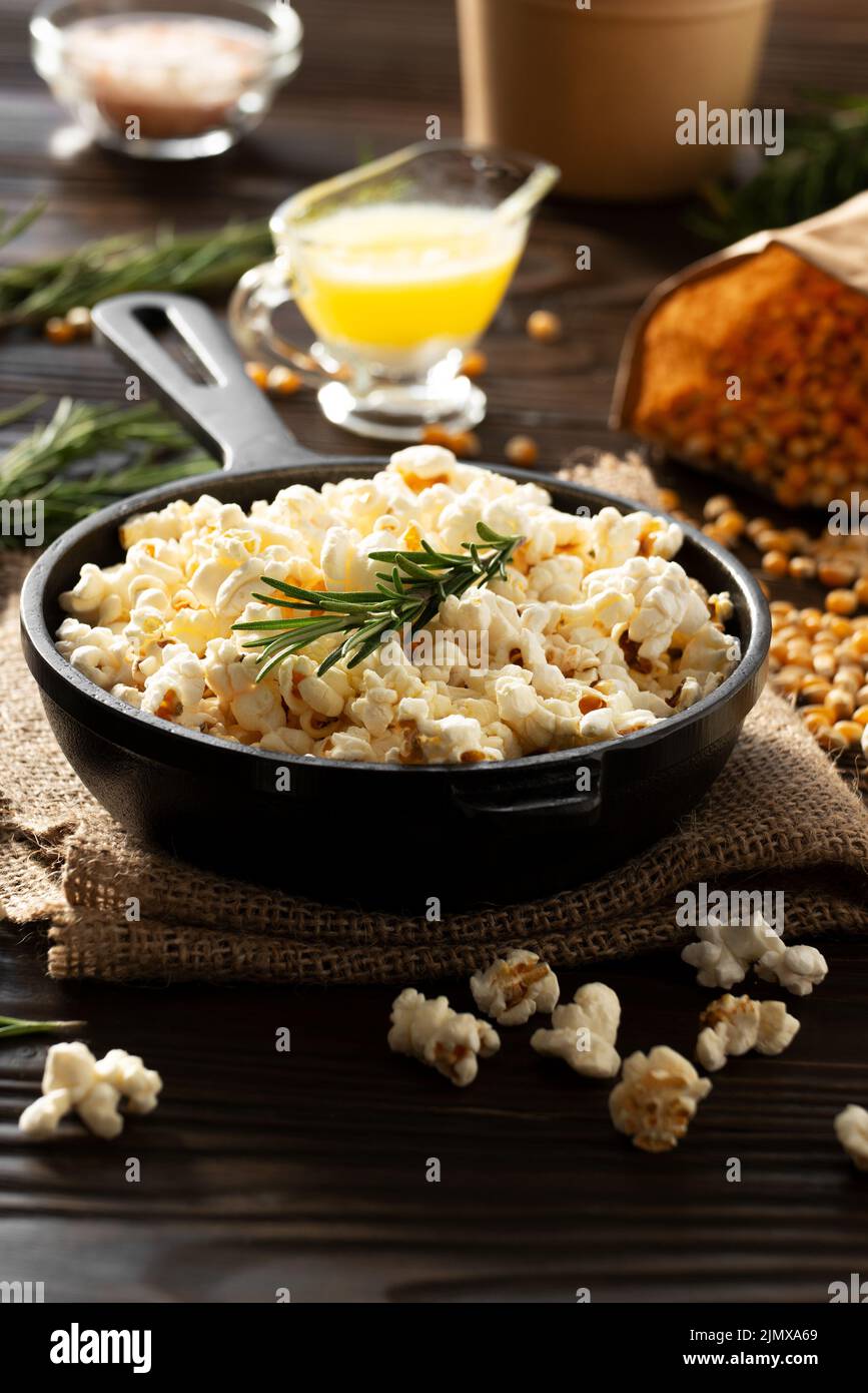 Popcorn in padella in ghisa con secchio di carta e burro fuso a parte Foto Stock