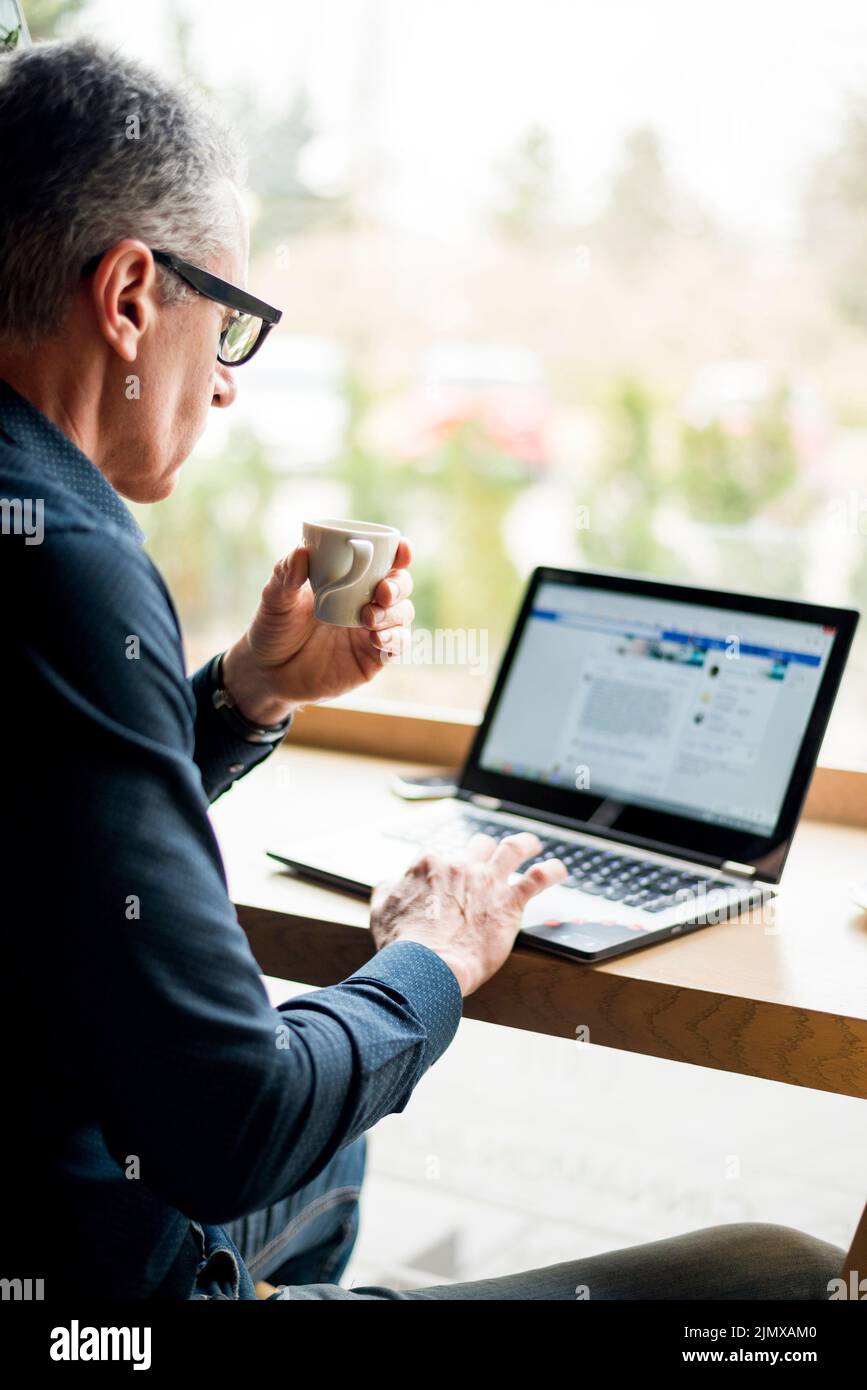 Un anziano uomo d'affari che lavora un computer portatile Foto Stock