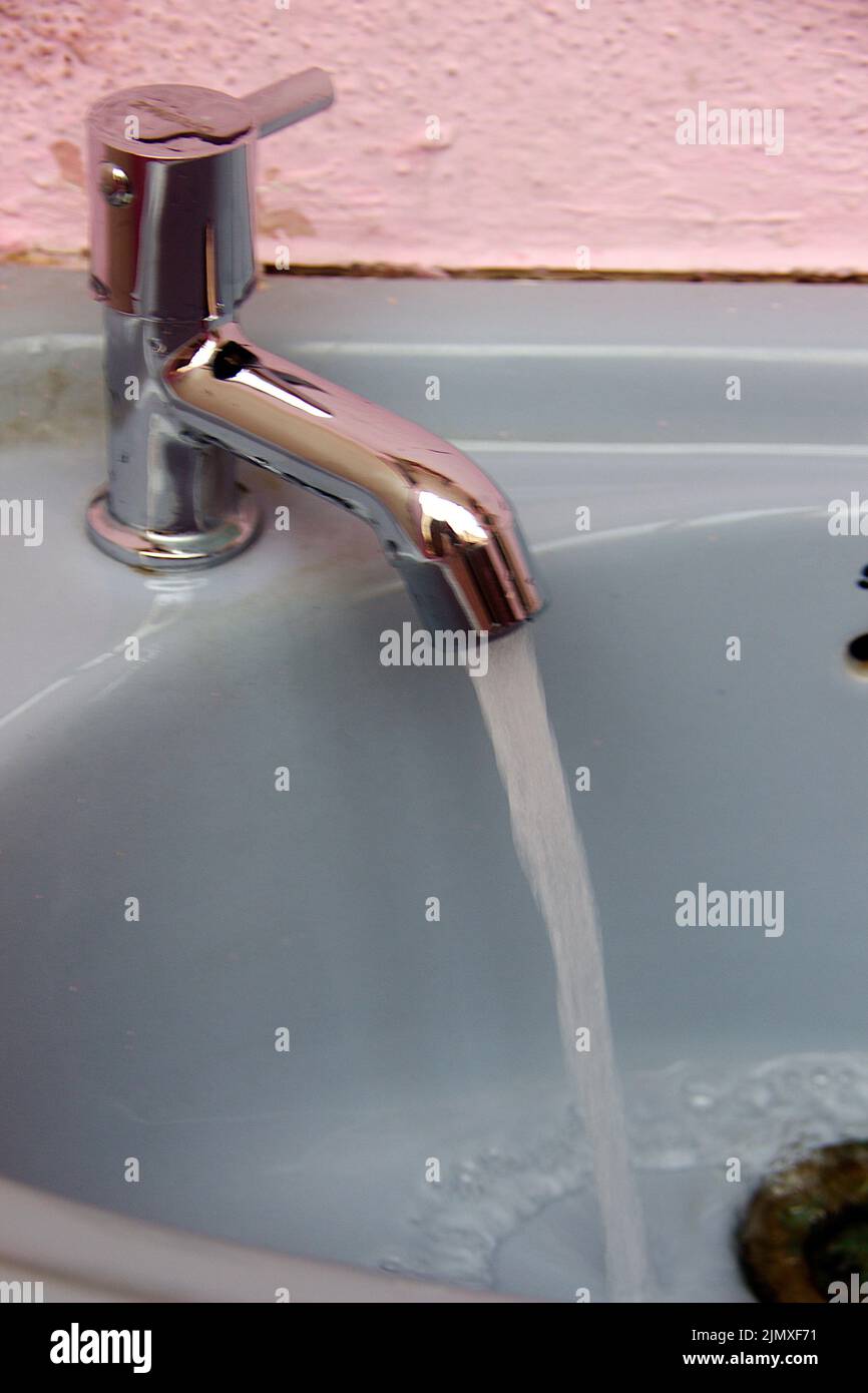 Acqua che sgorga attraverso il rubinetto del lavabo di colore grigio Foto Stock