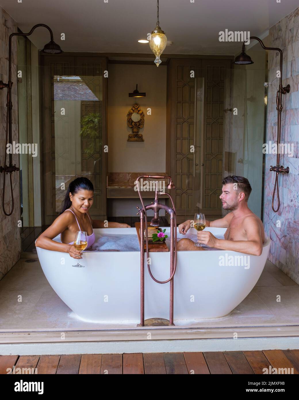 Romantica vasca da bagno con petali di rosa, vacanza di lusso nella vasca idromassaggio, coppia uomini e donne in bagno Foto Stock