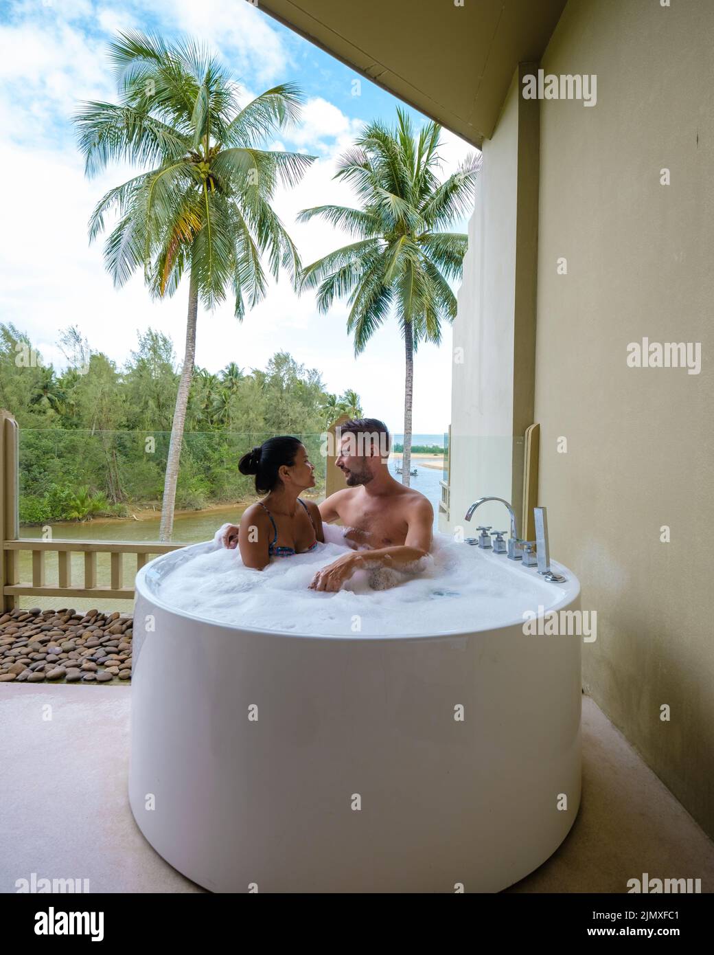 Romantica vasca da bagno con petali di rosa, vacanza di lusso nella vasca idromassaggio, coppia uomini e donne in bagno Foto Stock
