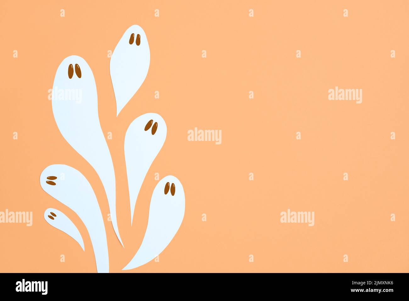 Halloween design, gruppo di simpatici fantasmi bianchi che volano su sfondo color arancio pastello, composizione trendy con spazio copia. Foto Stock