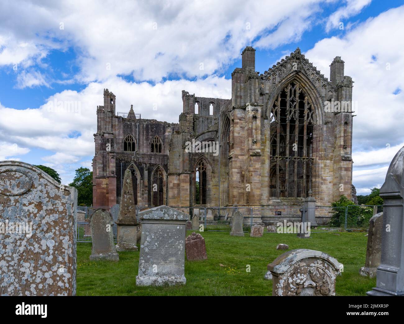 Vista sulle rovine dell'Abbazia di Melrose e le lapidi storiche nel cimitero della chiesa Foto Stock