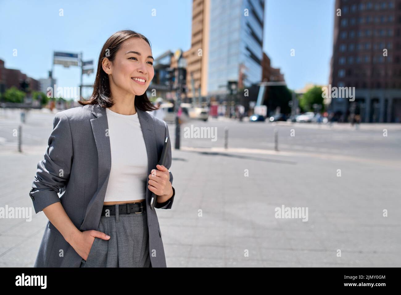 Giovane fiducioso felice imprenditore asiatico di affari in piedi sulla strada della città. Foto Stock