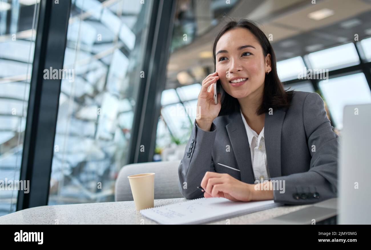 Giovane donna asiatica d'affari che indossa il vestito che parla al telefono che lavora in ufficio. Foto Stock