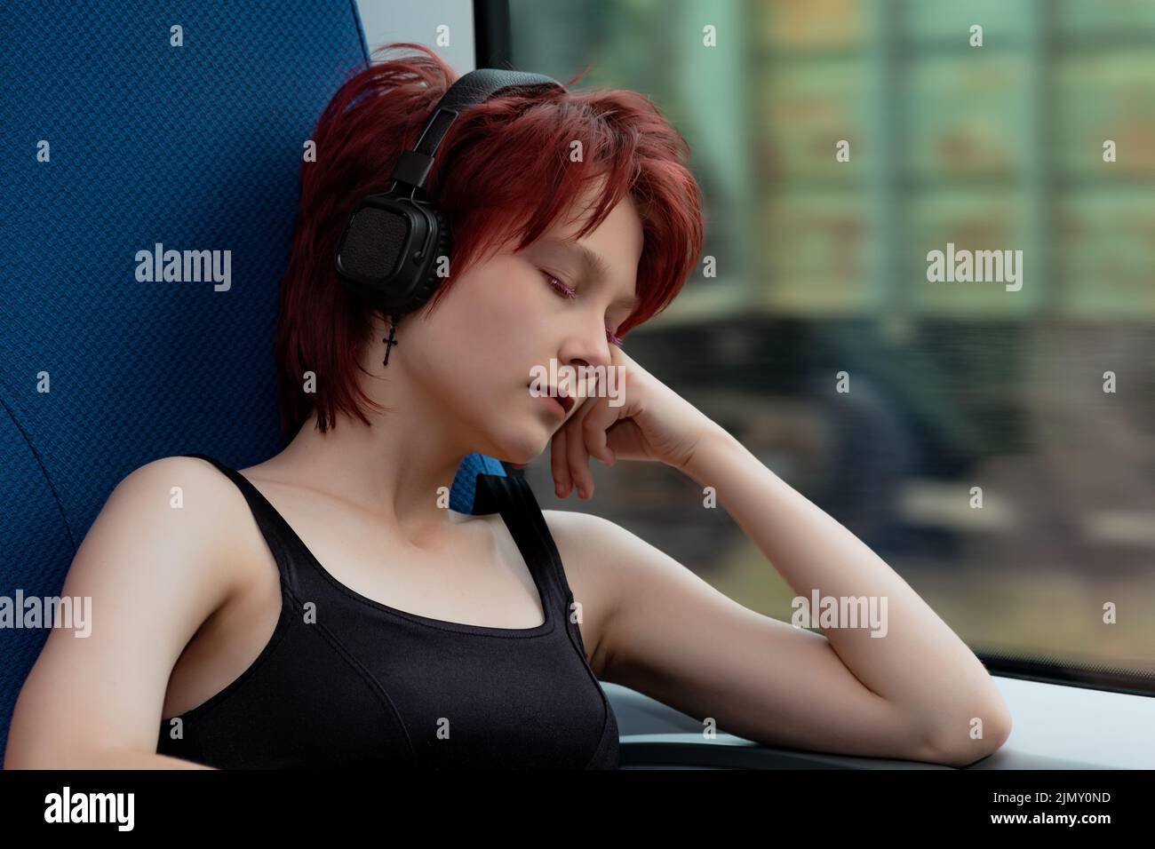 la giovane donna si è staccata in una carrozza di un treno suburbano in movimento, ascoltando la musica Foto Stock