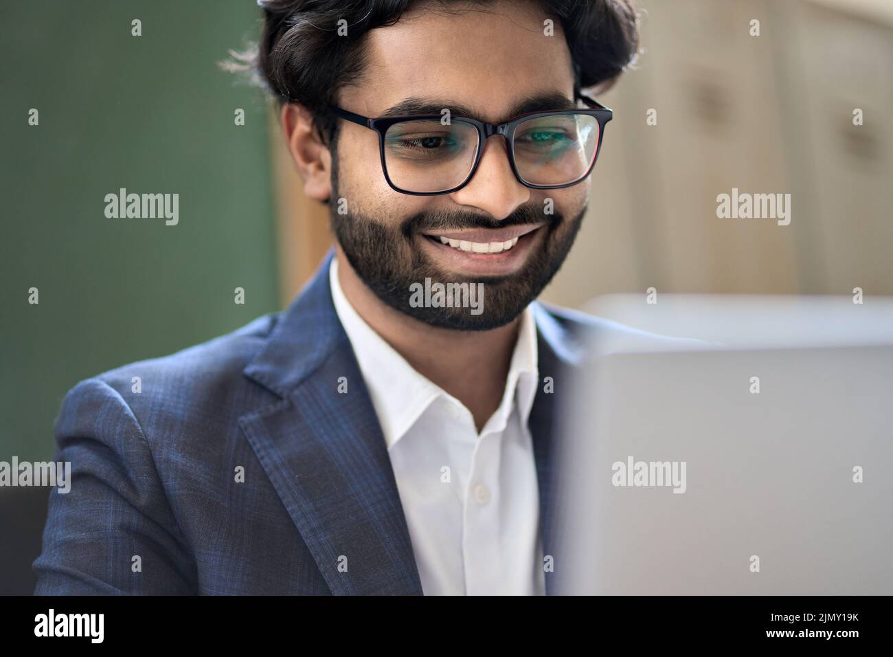Felice uomo d'affari indiano giovane dirigente vestito che lavora sul laptop. Foto Stock