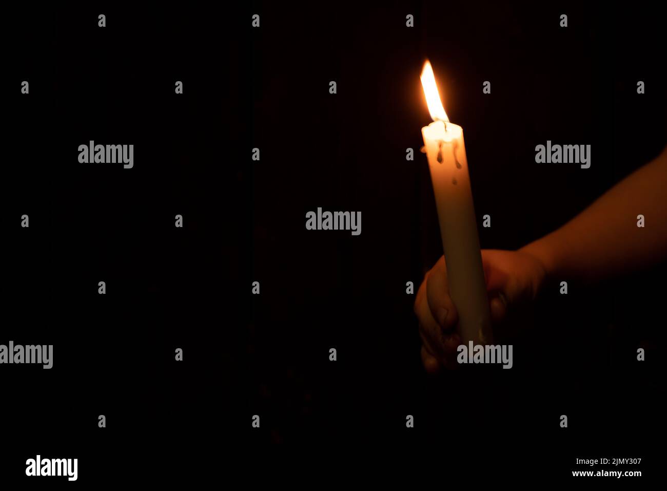 ragazzino che tiene una candela nel buio, fede e religione, preghiera e pace Foto Stock