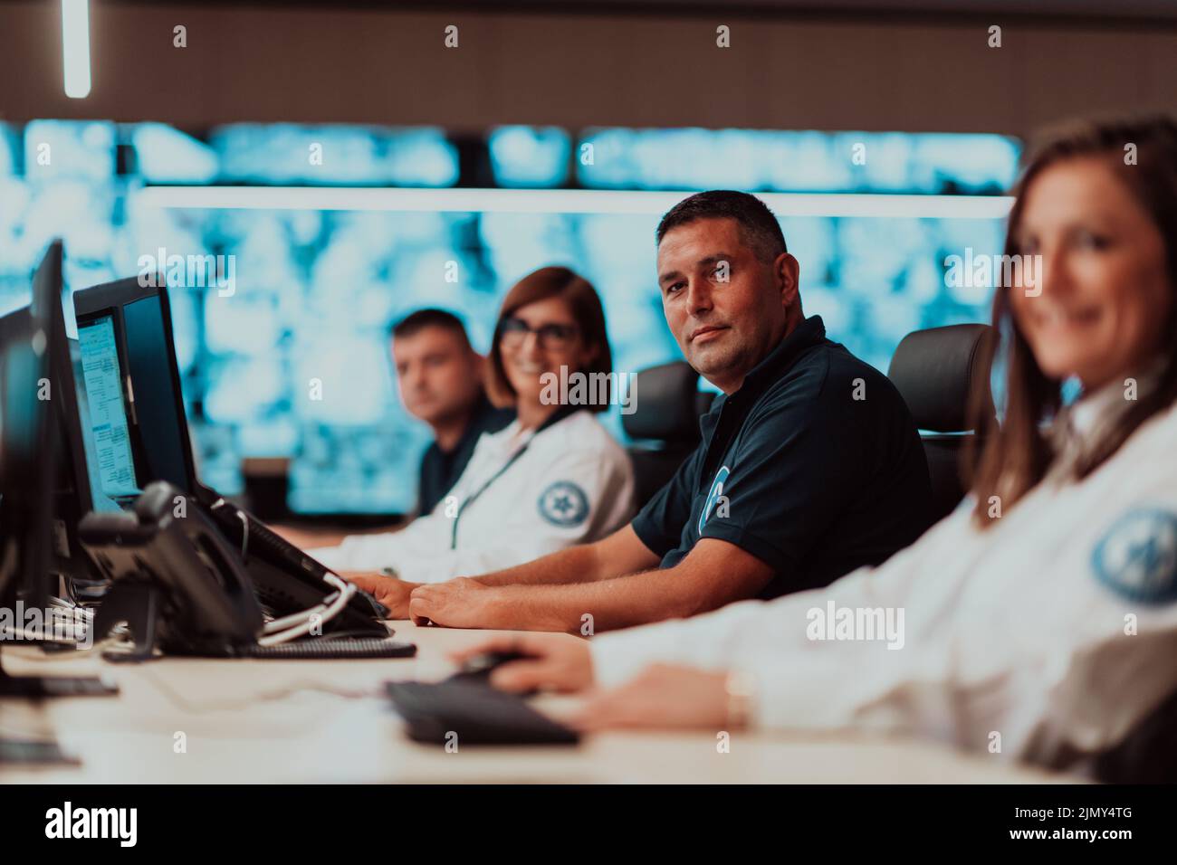 Gruppo di operatori del data center di sicurezza che lavorano in una sala di monitoraggio TVCC guardando su più monitor Officer Monitoring Multi Foto Stock