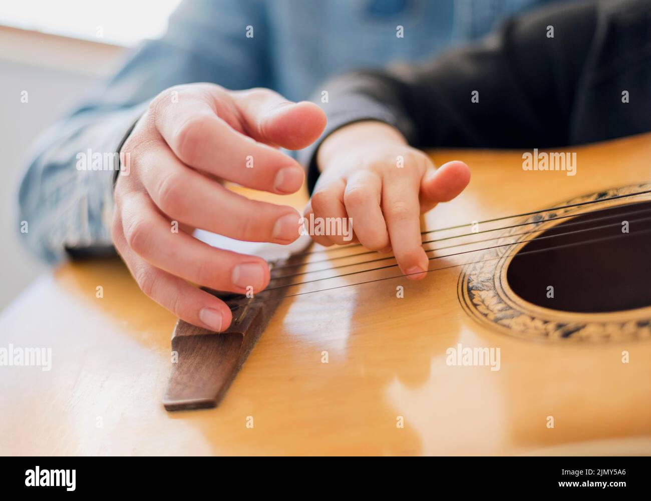 Bambino insegnante ad angolo basso che tiene la chitarra Foto Stock