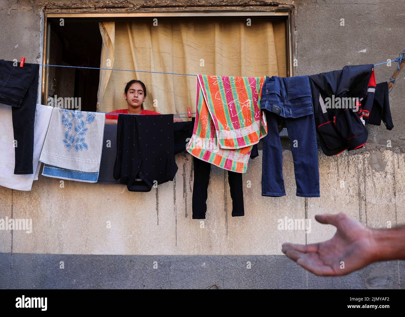 Una ragazza palestinese guarda da una finestra della sua casa che è stata danneggiata durante i combattimenti Israele-Gaza, come sostiene il cessate il fuoco, a Gaza City il 8 agosto 2022. REUTERS/Suhaib Salem Foto Stock
