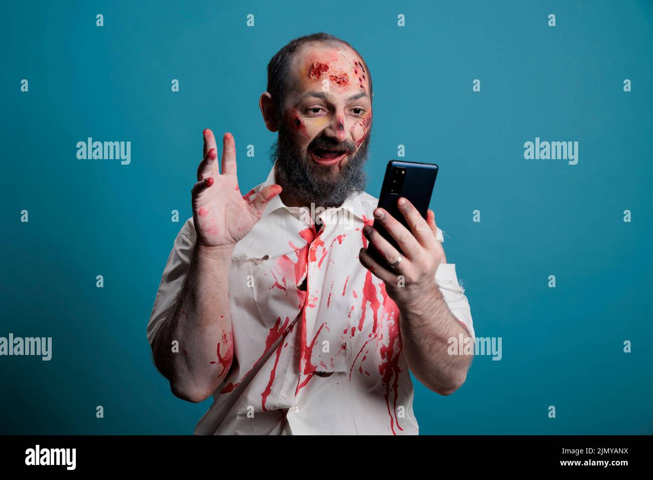 Zombie terrificante utilizzando la videoconferenza sullo smartphone, cercando di parlare in videoconferenza remota e in modo spaventoso. Mostro mortale e cervello che mangiano il cadavere usando la teleconferenza. Foto Stock