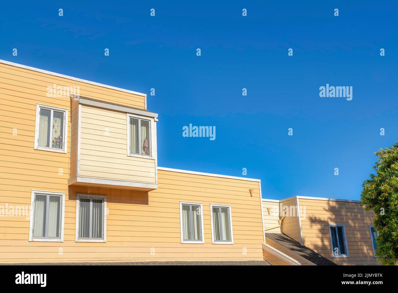 Edificio di appartamenti situato a San Francisco, California. Esterno di un appartamento con struttura a tetto piatto e lap side in legno giallo e beige. Foto Stock
