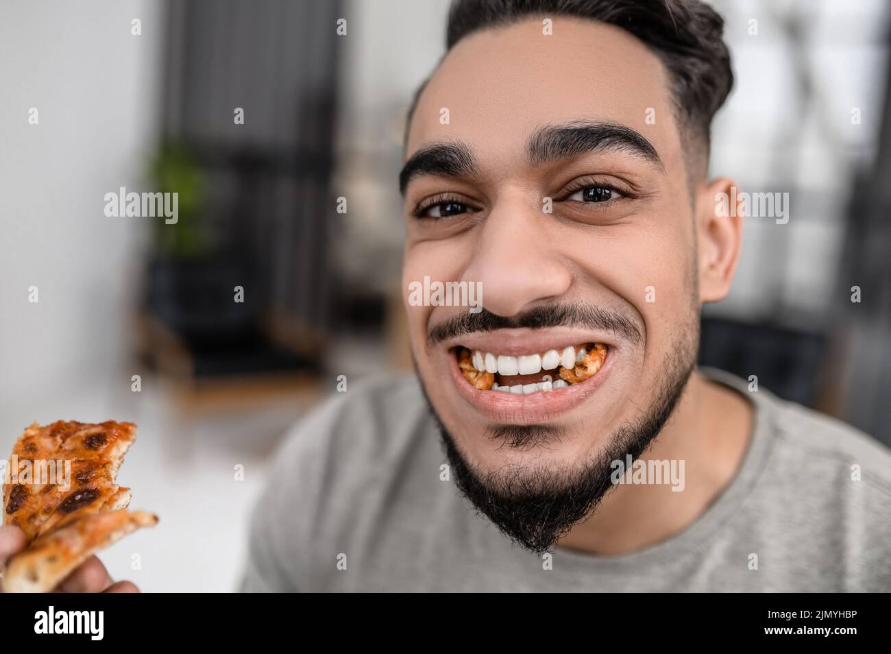 Uomo che mangia la pizza sorridendo alla macchina fotografica Foto Stock