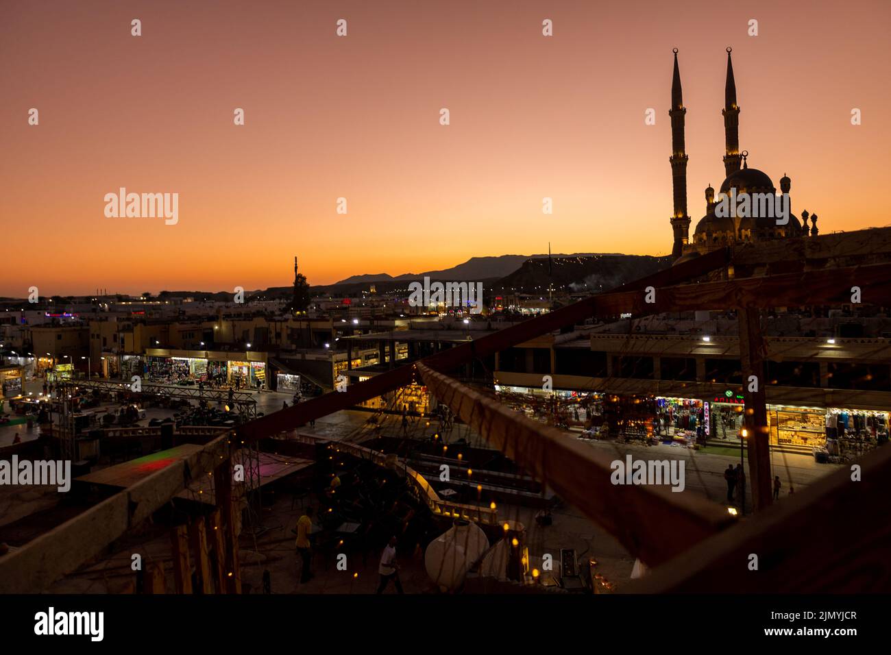 Sharm El Sheikh, Egitto - 4 novembre 2021: Vista panoramica dall'alto della moschea di al Sahab e della città vecchia al tramonto. Silhouette di persone nell'area dello shopping con souvenir in lucentezza di luci notturne. Foto Stock