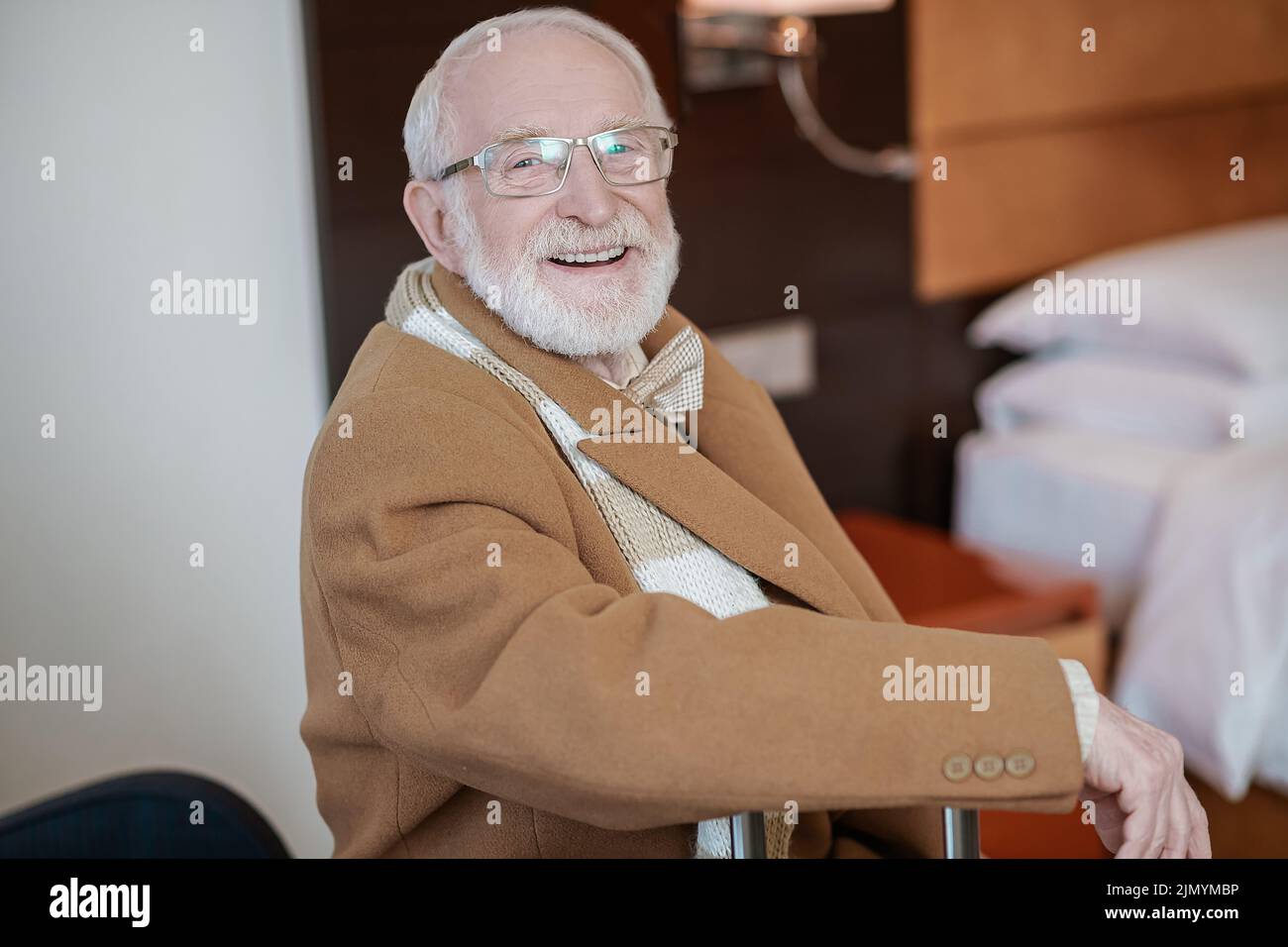 Gentiluomo bearded seduto in una poltrona in un hotel Foto Stock