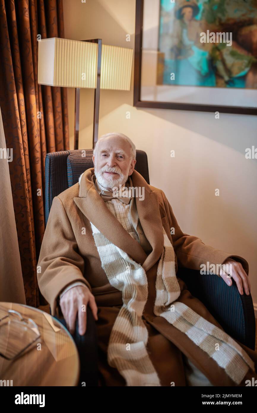 Gentiluomo bearded seduto in una poltrona in un hotel Foto Stock