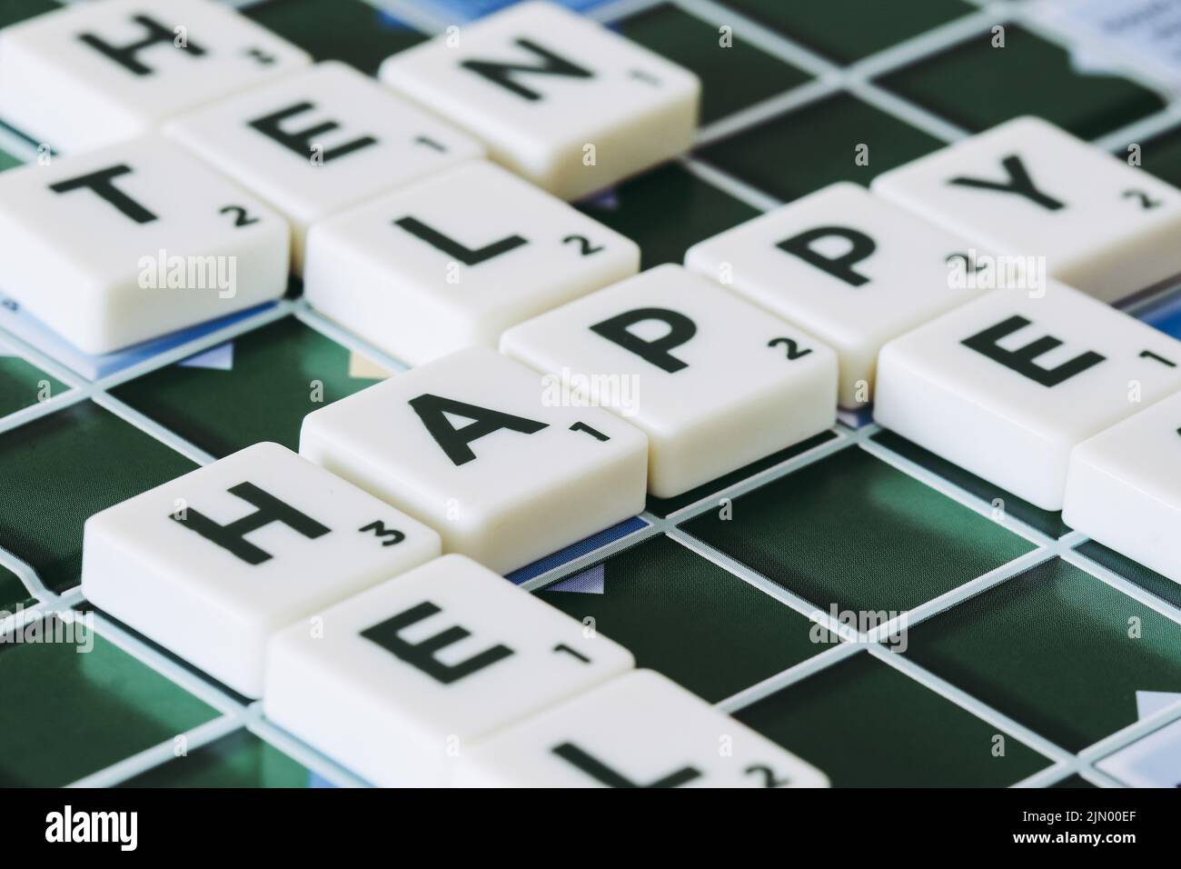 La parola felice fatta dei pezzi scrabble blocca le lettere a bordo Foto Stock