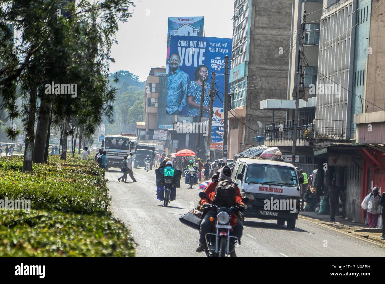 Nakuru, Kenya. 08th ago 2022. Una boda boda che porta un passeggero guida oltre un poster con l'immagine di Azimio la Umoja candidato presidenziale, Raila Odinga e il suo compagno di corsa, Martha Karua su una strada trafficata. Una sezione trasversale dei keniani sta tornando alle loro case di campagna prima del 9 agosto 2022, elezioni generali. Credit: SOPA Images Limited/Alamy Live News Foto Stock