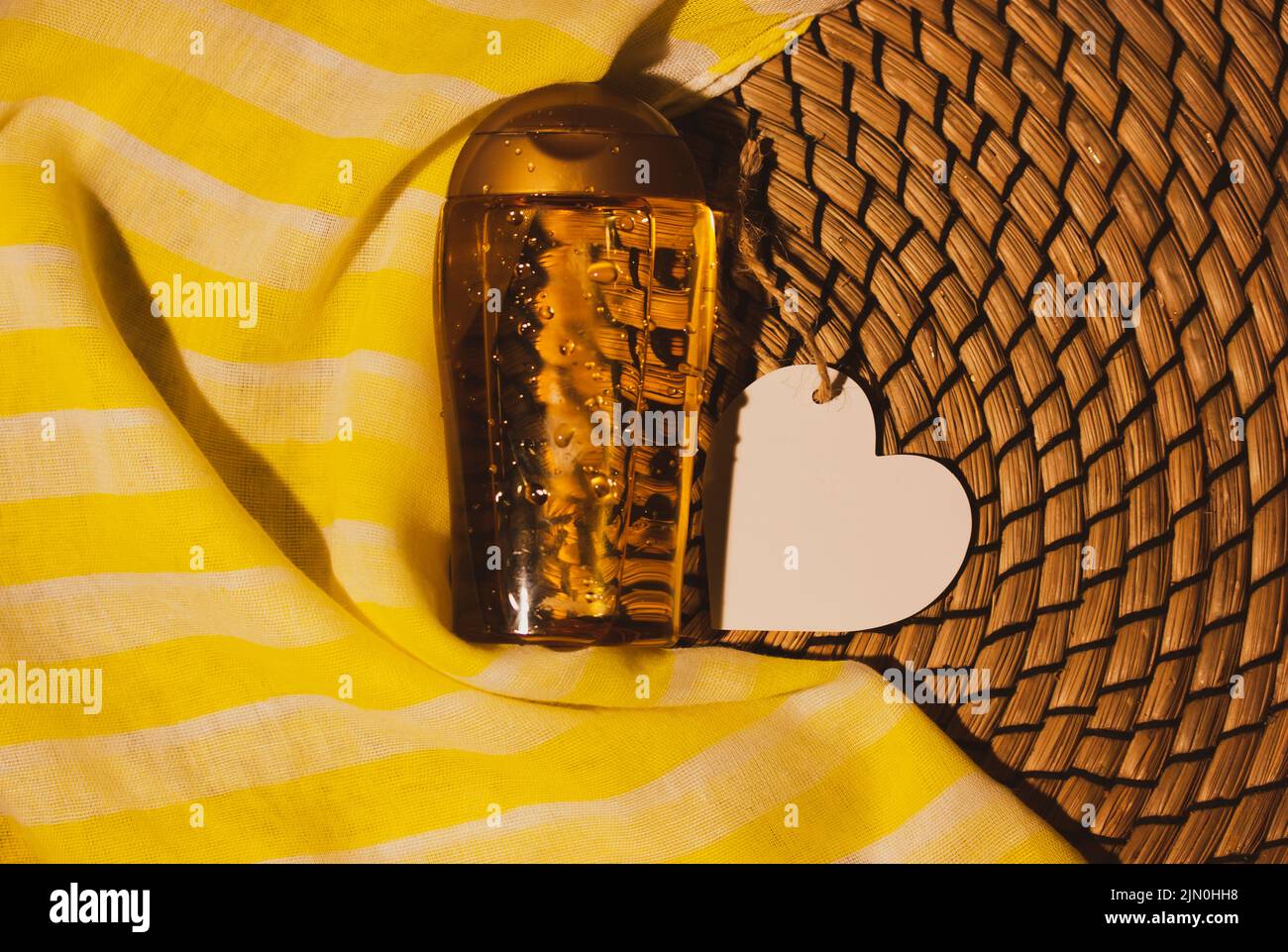 Corpo SPF protezione della pelle olio da concia, dopo concia su sfondo rattan, sciarpa tessile giallo. Cosmetici per il viso, amore per la cura del corpo, cocco oi Foto Stock