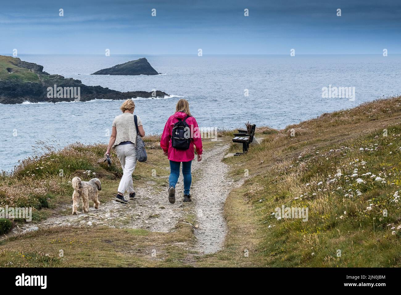 Due femmine che camminano con un cane lungo un sentiero costiero su Pentil poinbt East a Newquay in Cornovaglia in Inghilterra nel Regno Unito. Foto Stock