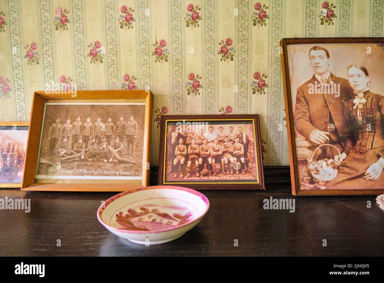 Famiglia, militari e la squadra di sport vecchie fotografie su una libreria. In una ricreazione di una tipica casa operaia generica, casa dal 1927 a Blaenavon Iron Foto Stock