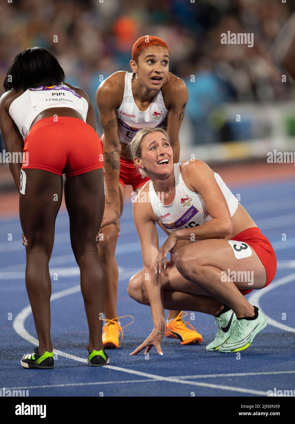 Ama Pipi, Jessie Knight e Jodie Williams d'Inghilterra aspettano di ascoltare il risultato della finale femminile del relè 4x400m al Commonwealth Games di Alexa Foto Stock