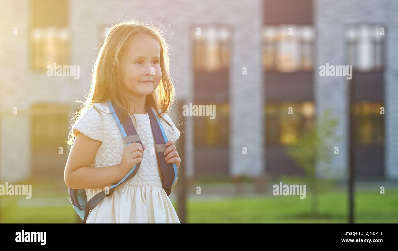 La ragazza felice va a scuola sorridendo alla luce del tramonto posteriore Foto Stock
