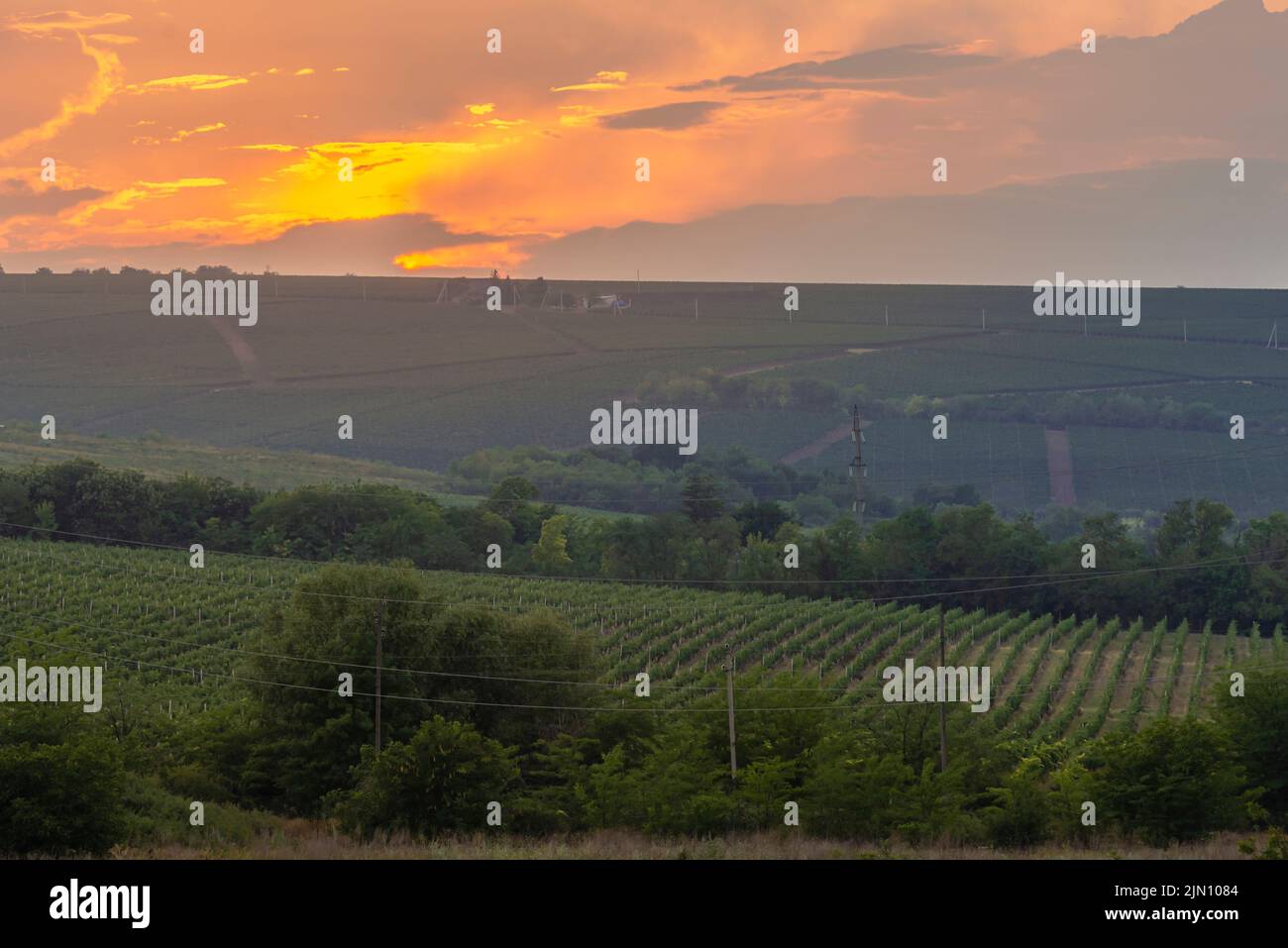 Paesaggio rurale campo e un pittoresco cielo durante il tramonto drammatico vivido colline campagna al tramonto in luce di sera. Paesaggio rurale Foto Stock