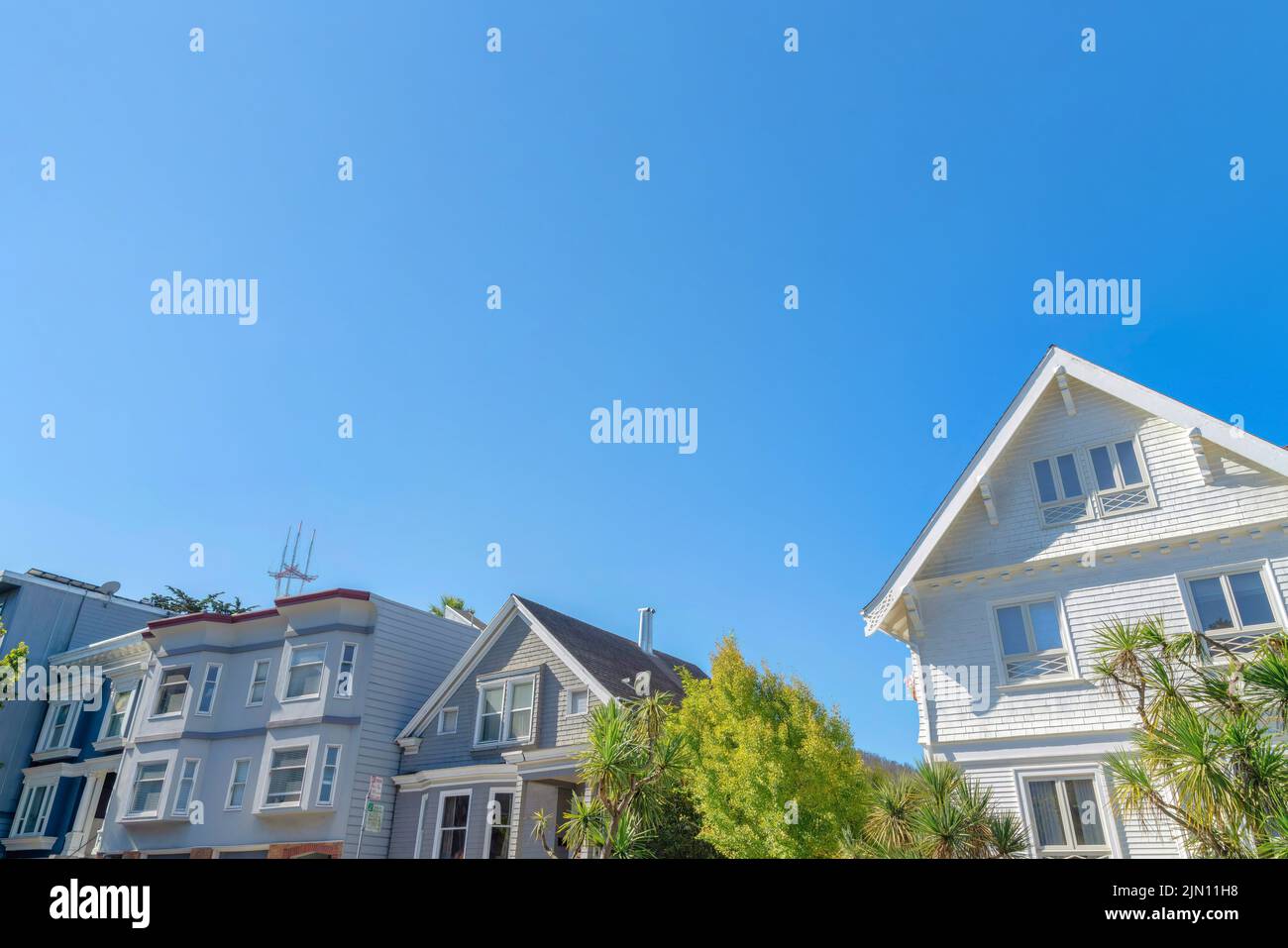 Vista dell'esterno anteriore delle case dal basso contro il cielo blu chiaro a San Francisco, CA. Ci sono due case sulla sinistra con struttura a tetto piatto Foto Stock