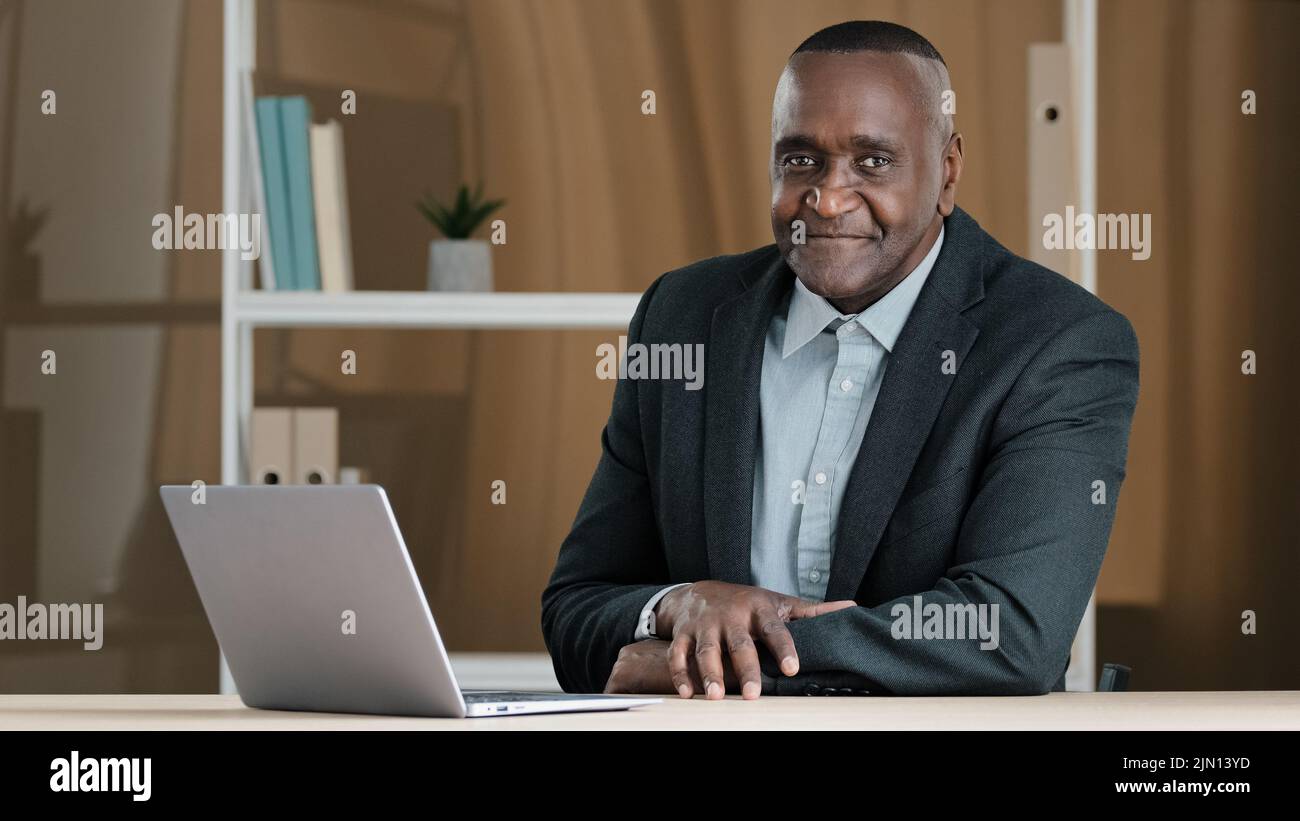 Ritratto di anziano anziano africano anziano uomo d'affari seduto in ufficio al tavolo con il laptop annuendo testa rispondendo sì approvazione sostenendo la buona idea Foto Stock