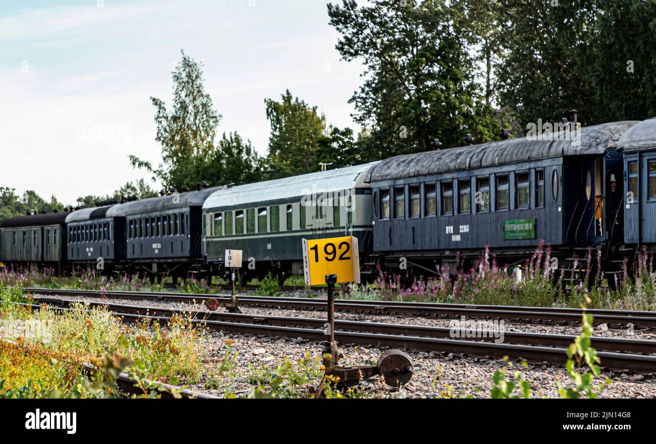 Un passaggio in un cantiere ferroviario a Pasila, Helsinki, Finlandia. Le erbacce stanno crescendo sulla pista. Sullo sfondo, vagoni ferroviari d'epoca. Foto Stock