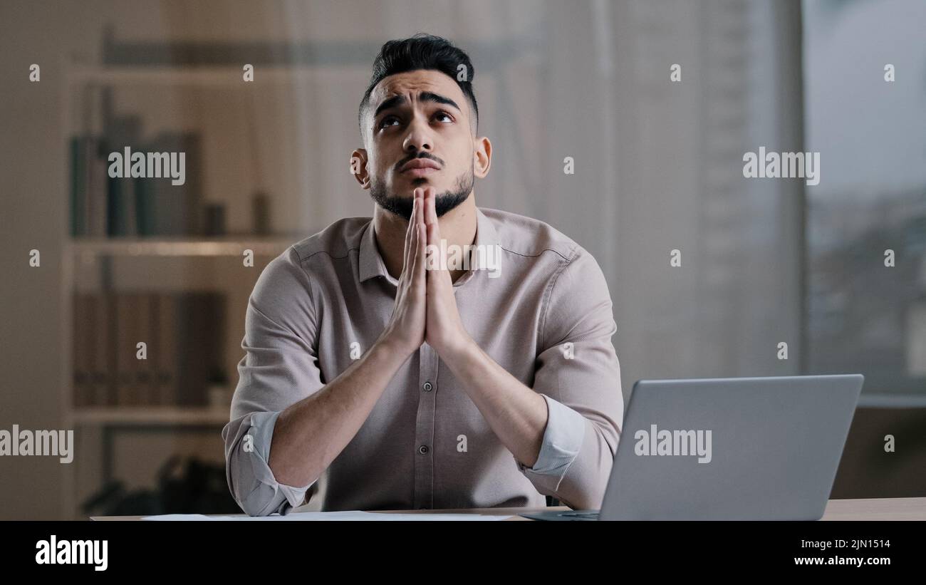 Frustrato giovane ispanico maschio analista religioso business uomo sentire stress controllare i documenti finanziari chiedere aiuto concentrarsi mente a problema sedersi con Foto Stock