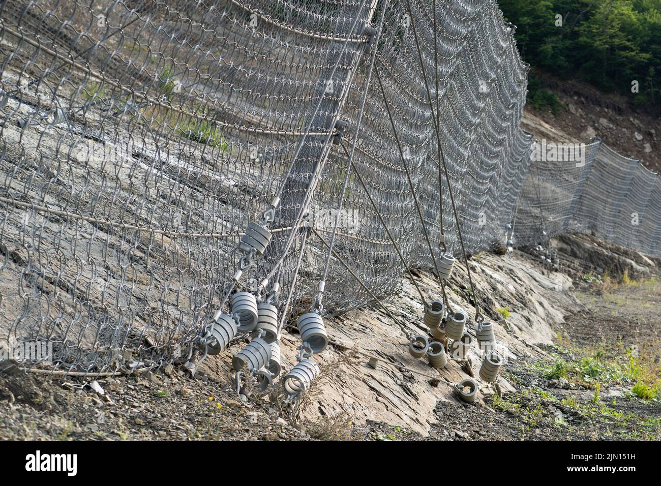 Sistema di barriera attivo e robusto con rete metallica lungo la strada, freno per la caduta di rocce. Foto Stock