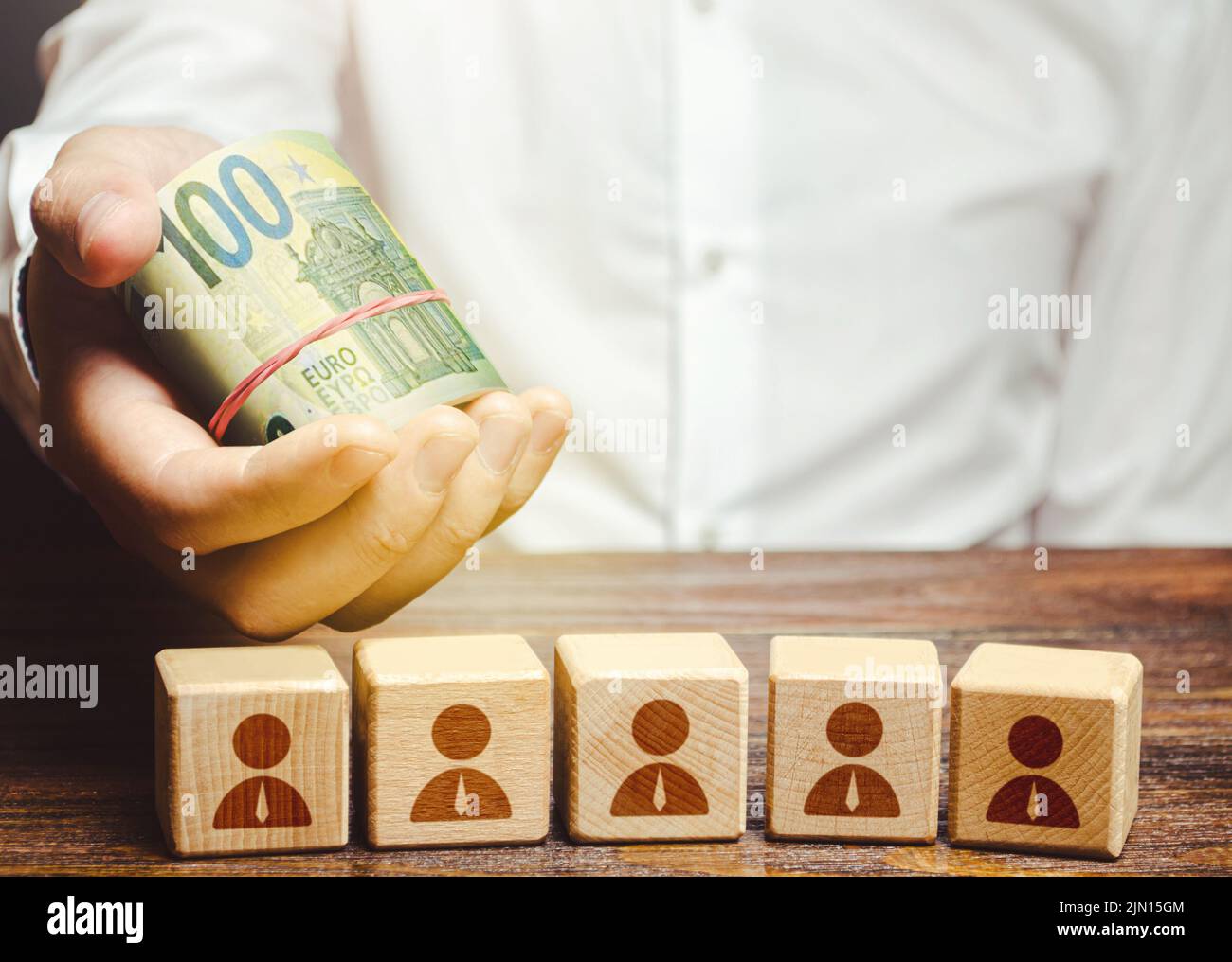 Uomo d'affari che tiene un rotolo di euro bollette di denaro sui blocchi dipendenti. Calcolo del profitto della società. Lavoro del personale addetto ai pagamenti, ottimizzazione dei costi. CA Foto Stock