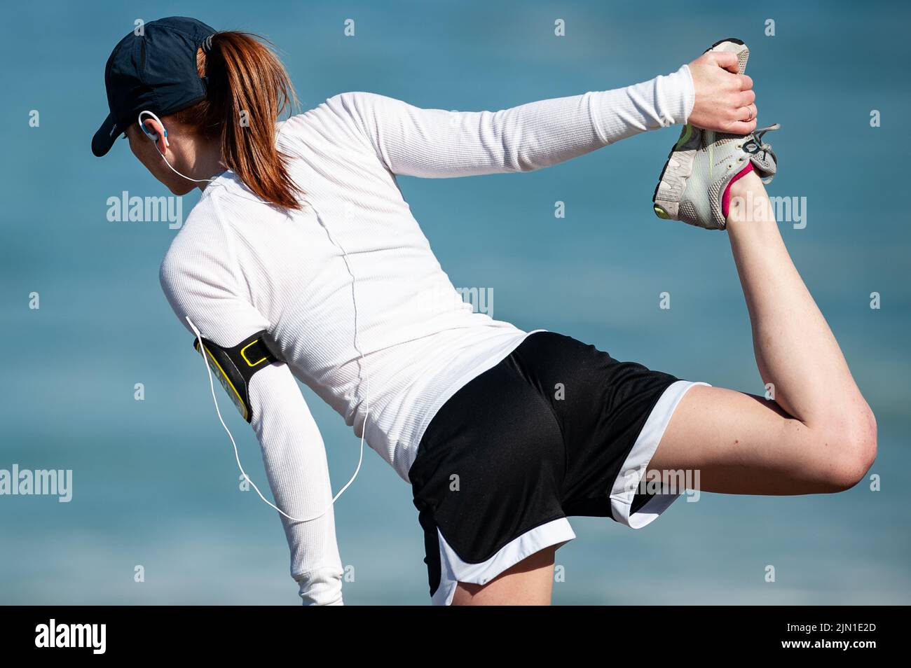 Immagine di una donna che si allunga prima della sua corsa mattutina sulla spiaggia. Secondo riscaldamento, Beach Runner, San Francisco, California, salute, Benessere, esercizio fisico Foto Stock