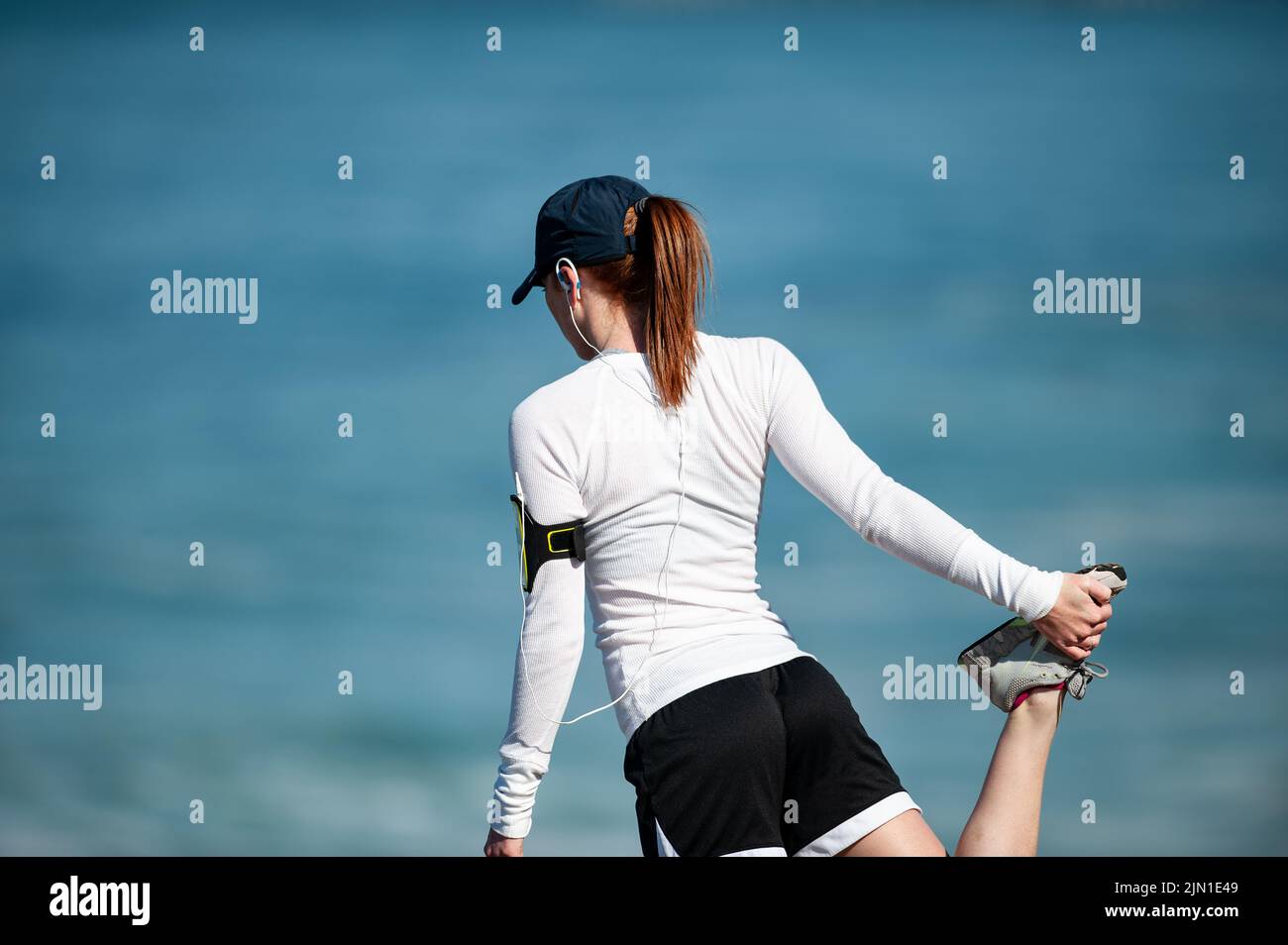 Immagine di una donna che si allunga prima della sua corsa mattutina sulla spiaggia. Secondo riscaldamento, Beach Runner, San Francisco, California, salute, Benessere, esercizio fisico Foto Stock