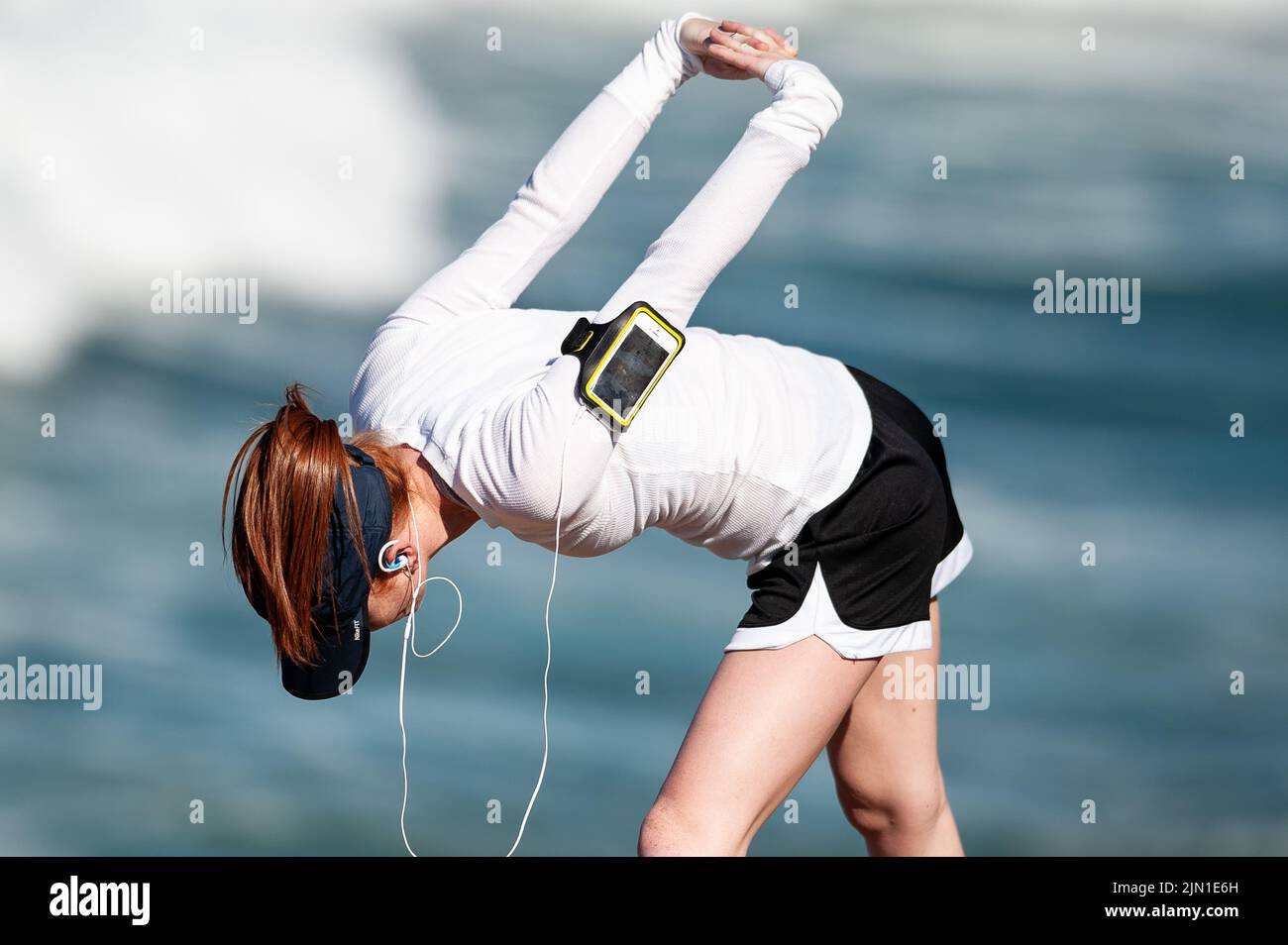 Immagine di una donna che si allunga prima della sua corsa mattutina sulla spiaggia. Secondo riscaldamento, Beach Runner, San Francisco, California, salute, Benessere, esercizio fisico Foto Stock