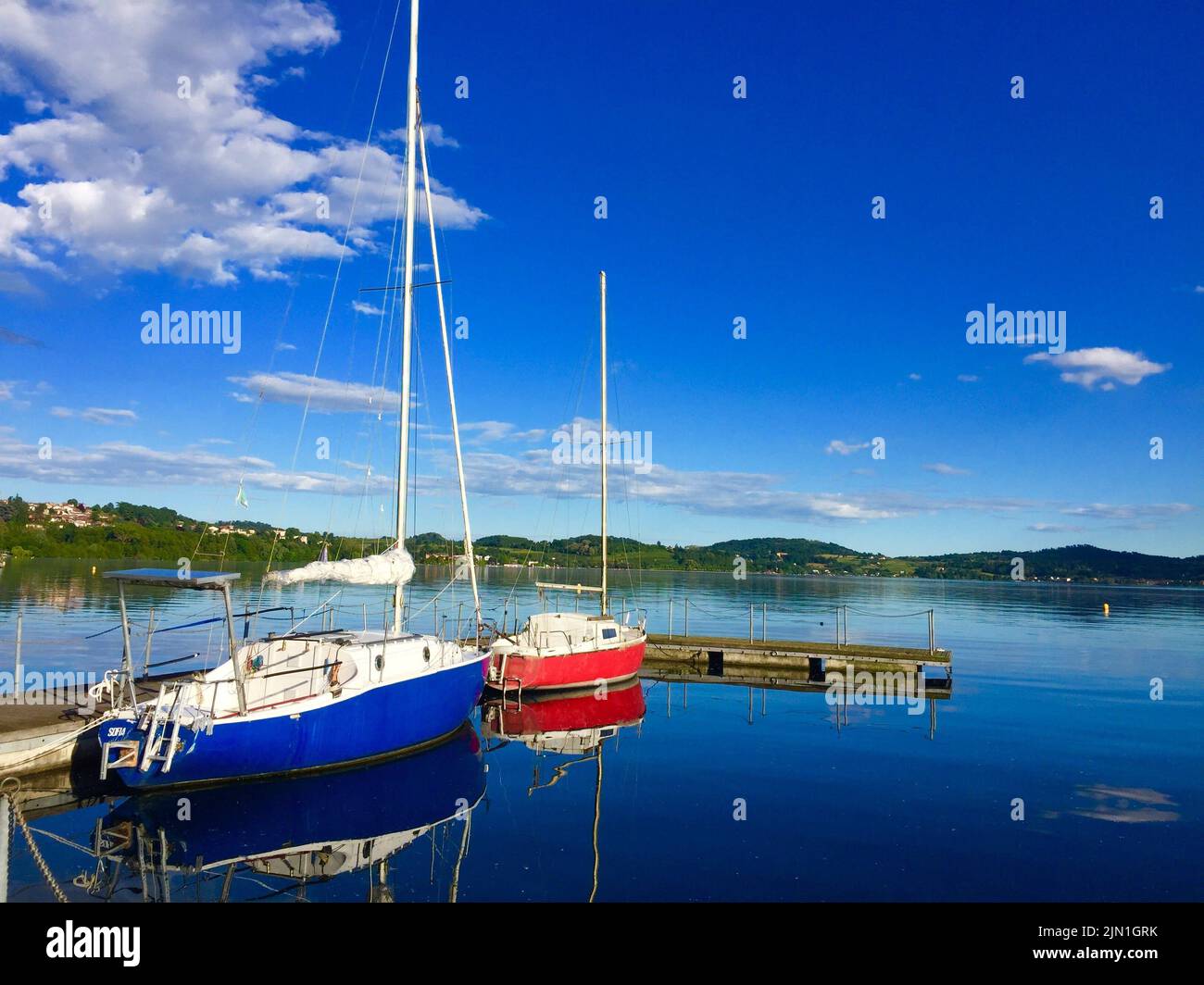 Vista delle barche da pesca ormeggiate al porto turistico nelle giornate di sole in baia sul lago di Viverone con riflessi sulla superficie dell'acqua Foto Stock