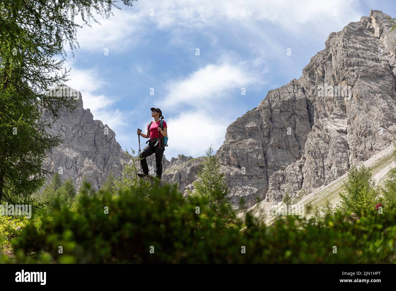 Donna escursionista in piedi su una roccia su un sentiero per il Karlsbader Hütte e il lago Laserzsee nelle Dolomiti di Lienz, Tirolo orientale, Austria Foto Stock
