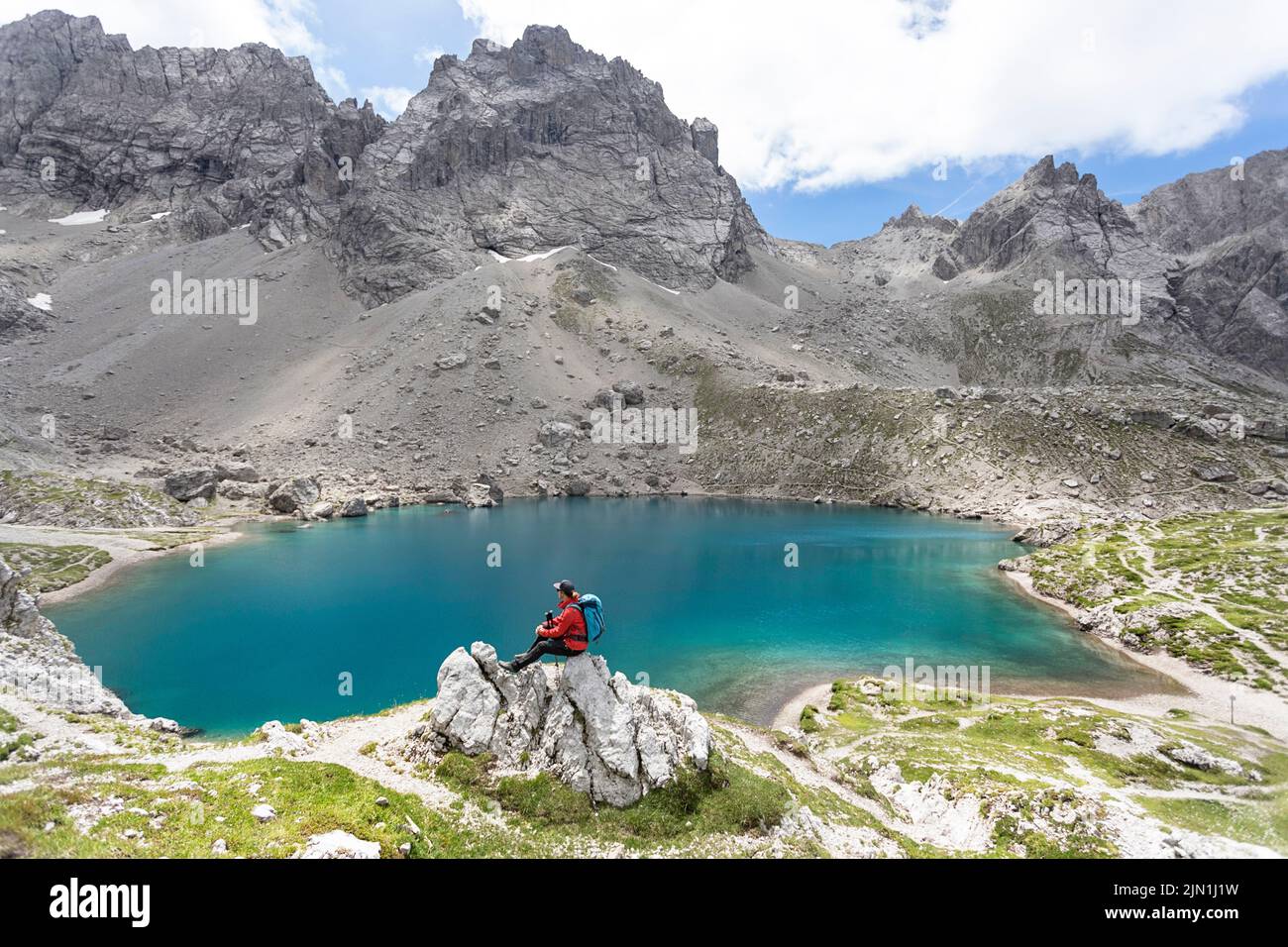Donna escursionista seduto su una roccia nell'incontaminato lago alpino di Laserzsee, sopra la città di Lienz, nelle Dolomiti di Lienz, Tirolo orientale, Austria, Europa Foto Stock