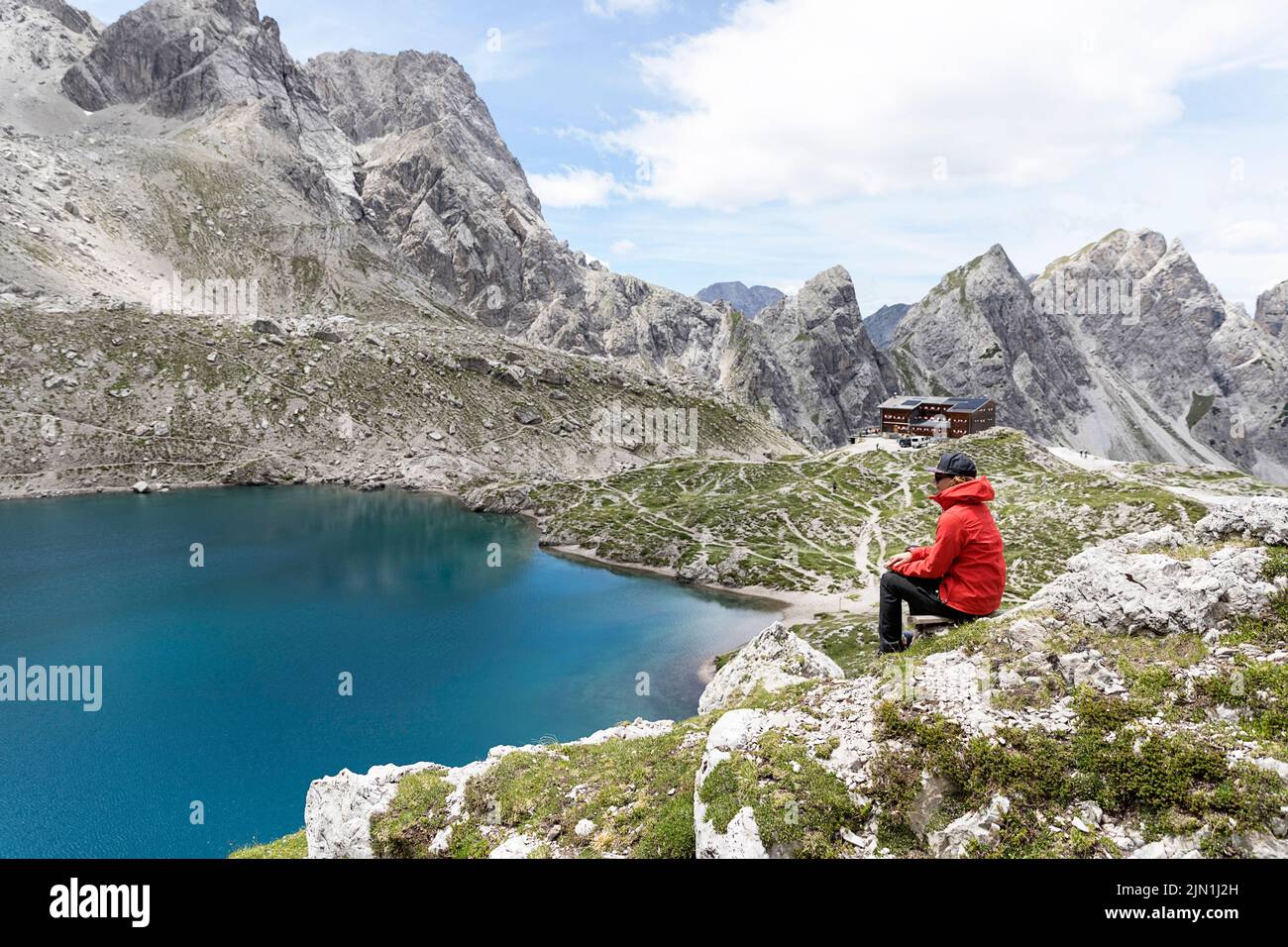 Donna escursionista seduta su una panchina di legno presso l'idilliaco lago alpino Laserzsee, sopra la città di Lienz, nelle Dolomiti di Lienz, nel Tirolo orientale, in Austria, in Europa Foto Stock