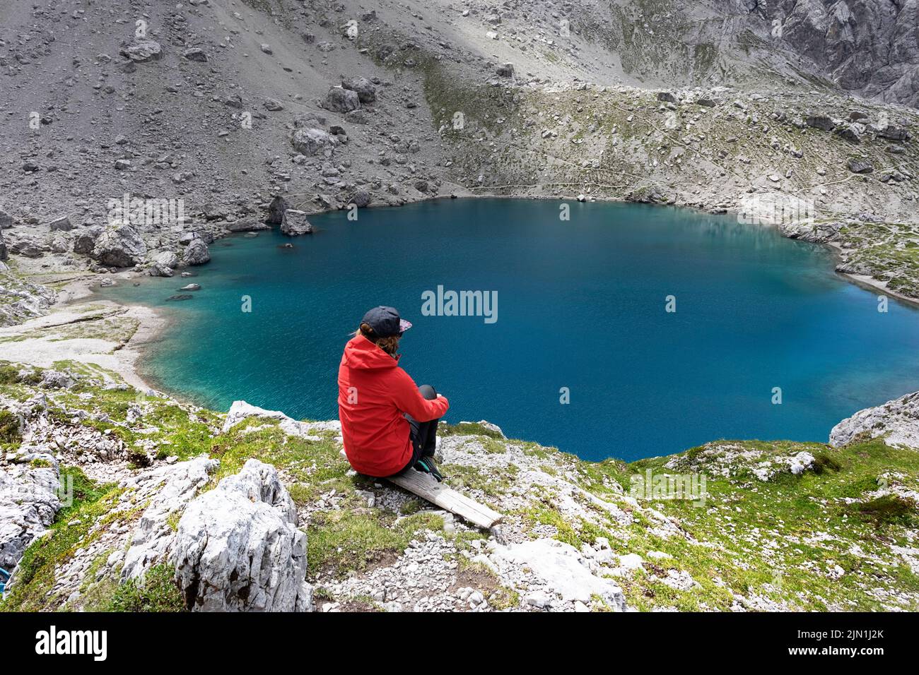Donna escursionista seduto su una panchina nel lago alpino Laserzsee, sopra la città di Lienz, nelle Dolomiti di Lienz, Tirolo Orientale, Austria, Europa Foto Stock