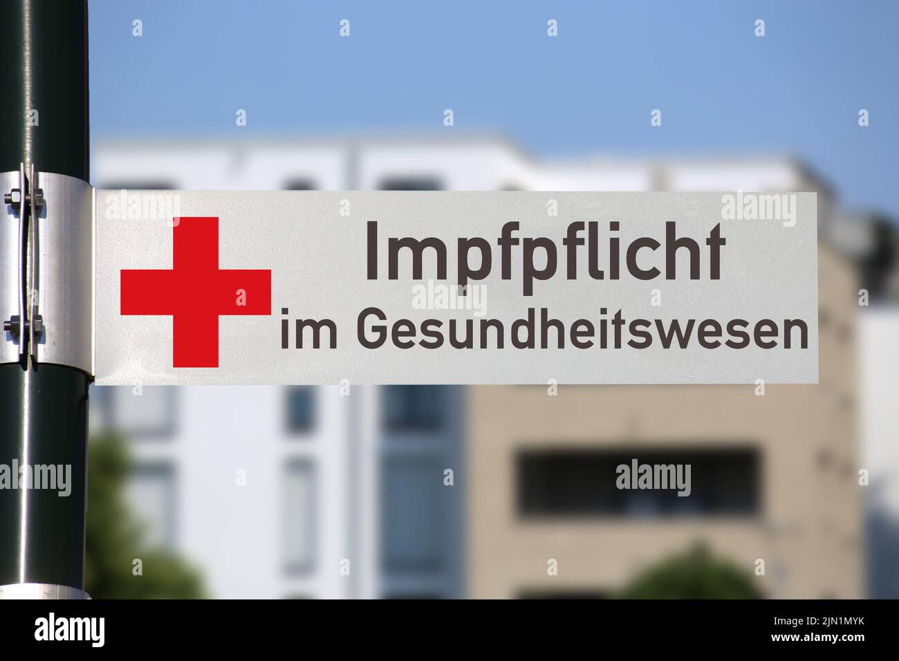 Symbolbild Impfflicht im Gesundheitswesen: Straßenschild mit rotem Kreuz und entsprechender Aufschrift vor einem Gebäude Foto Stock