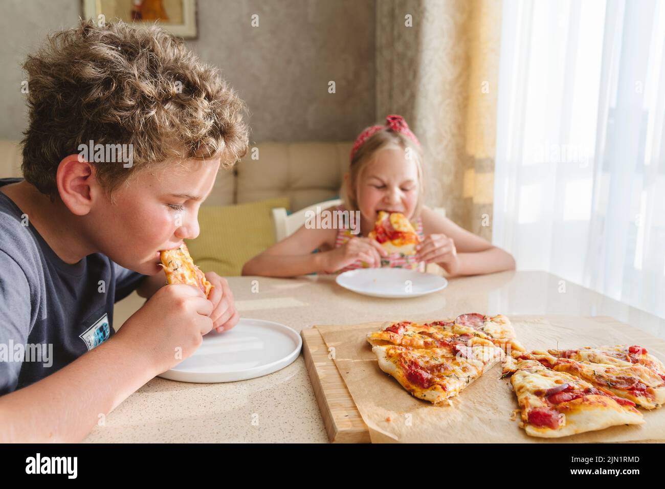 I bambini mangiano la pizza fatta in casa. Foto Stock