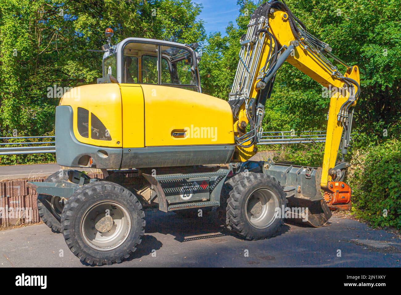 pala gommata grigia gialla con pala escavatrice al bordo di un cantiere Foto Stock