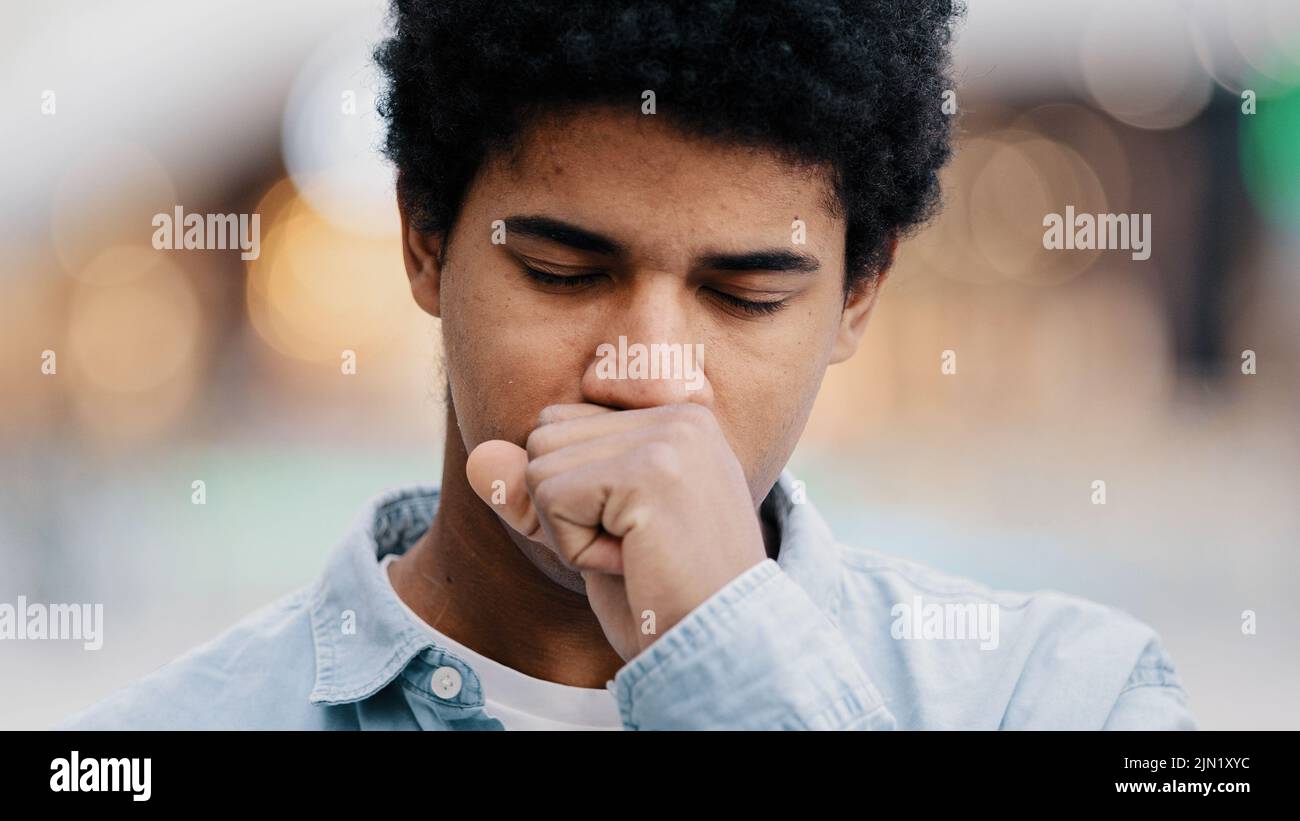 Ritratto maschile triste africano americano uomo malato ragazzo interno tosse coprire la bocca con mano mal di gola problemi con respirazione covid sintomi asma Foto Stock